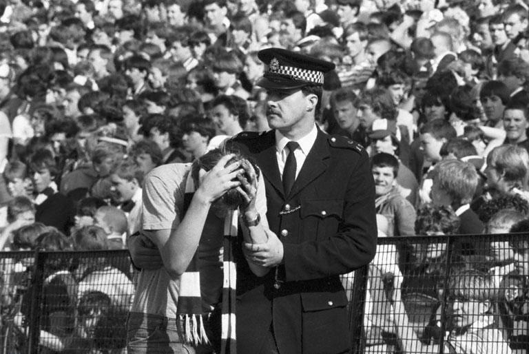 A policeman helps an injured fan after crowd trouble during the Hibs v Hearts Edinburgh derby football match at Easter Road in August 1984. Final score 1-2 to Hearts